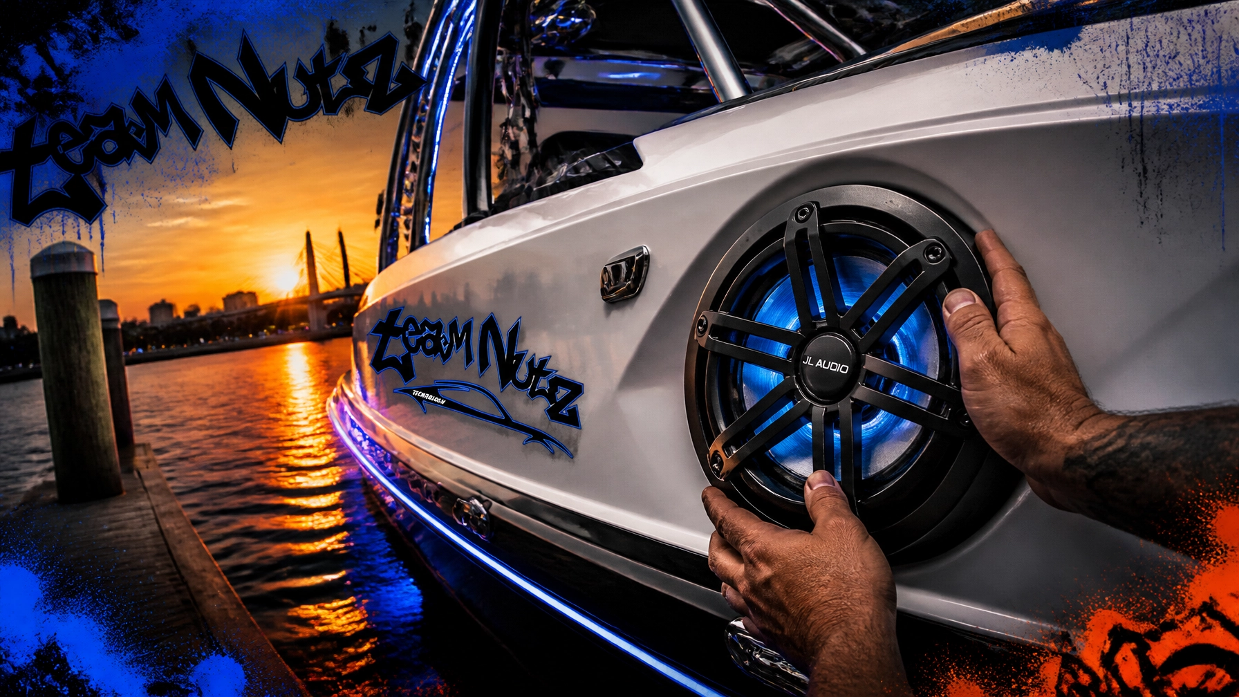 Hands adjust a blue-lit JL Audio subwoofer on the side of a white speedboat at sunset by the water.
