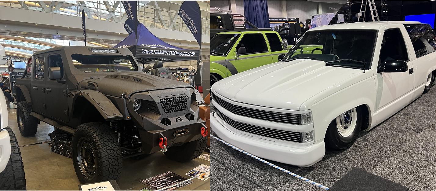 Side-by-side: on the left a matte black armored off-road SUV with large tires and rugged bumper at an indoor show; on the right a white customized lowered pickup with a wide grille and shaved sides, also at the show.