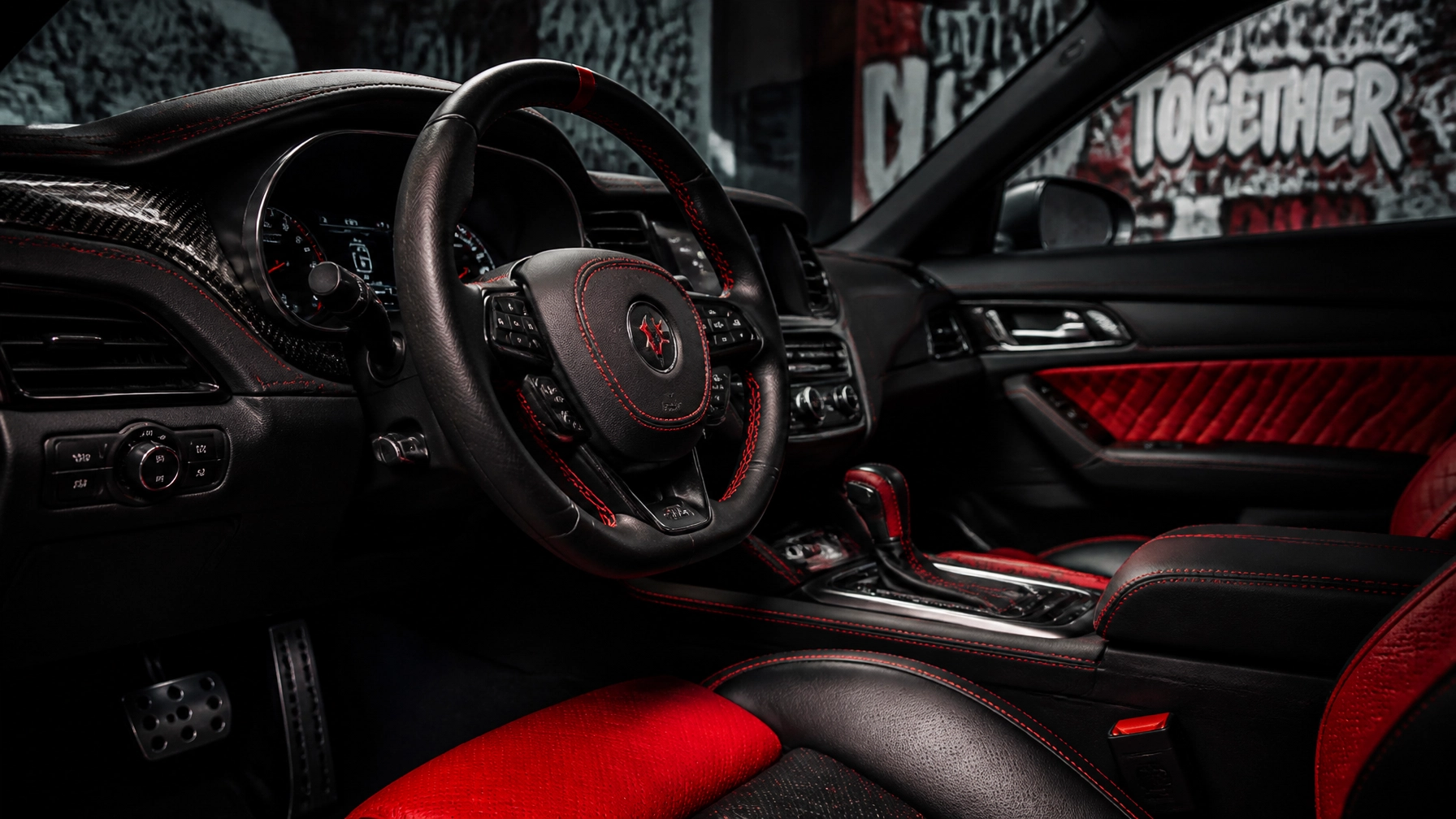 Luxury car interior featuring black leather with red contrast stitching, a sporty steering wheel, and red-accented seats and panels.